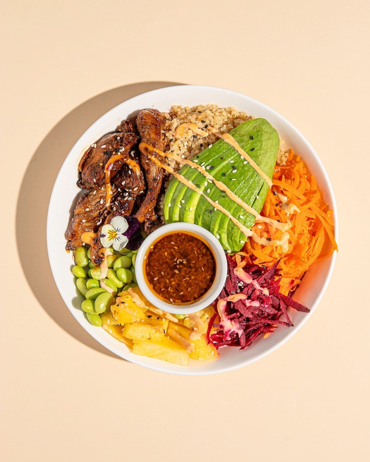 A quinoa bowl with avocado, edamame, carrot and beet